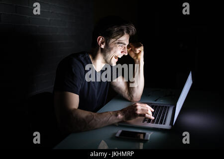 Junger Mann Arbeit am Computer in der Nacht im dunklen Büro arbeitet der Designer in der späteren Zeit. Hacker Stockfoto