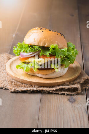 Hausgemachte Hamburger in Holzplatte auf alten hölzernen Hintergrund Stockfoto