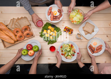 Abendessen mit Freunden genießen.  Draufsicht der Gruppe von Menschen, die Abendessen zusammen beim Sitzen am Tisch aus Holz Stockfoto