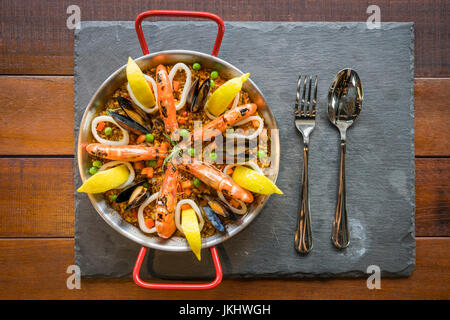 Paella mit Meeresfrüchten, Gemüse und Safran in der Draufsicht traditionelle Pfanne serviert. Stockfoto
