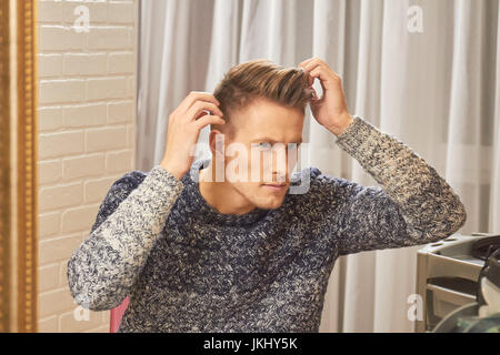 Junger Mann seine Haare zu überprüfen. Stockfoto