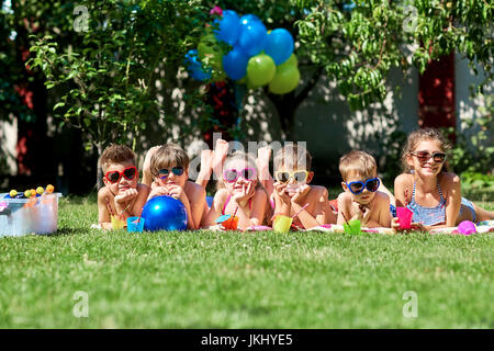 Gruppe von Kindern in Sonnenbrille auf dem Rasen im Sommer. Stockfoto