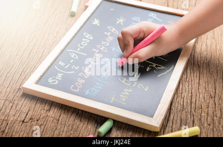 Kleine Hand schreiben auf einer Kreidetafel Abschluss mathematische Gleichungen auf Holz Hintergrund Stockfoto