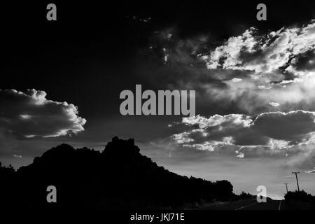 Eine schwarze und weiße Südwesten Szene in Santa Fe, New Mexico mit Moody Wolken, Felsformationen, und Telefonmasten. Stockfoto