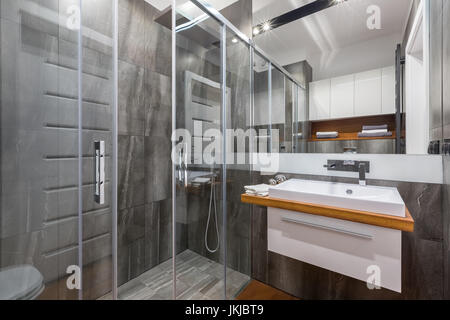 Graue Badezimmer mit begehbarer Dusche, Schrank Waschbecken und Spiegel Stockfoto