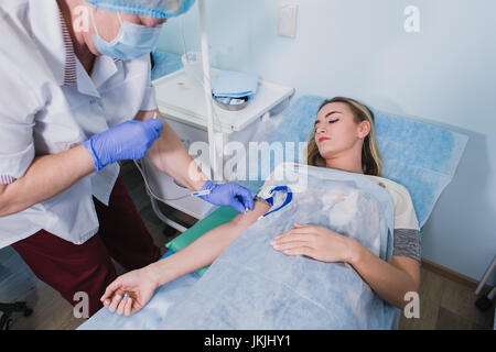 Krankenschwester macht eine Injektion mit einer Frau am OP-Tisch am Klinikum Vorbereitung Narkose medizinische Arztpraxis Konzept liegen. Stockfoto