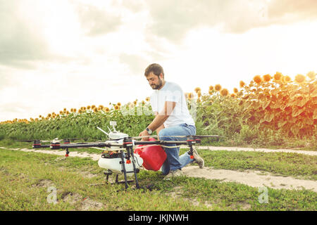 Junger Mann gießt Dünger für die Bewässerung in der Landwirtschaft-Drohne. Stockfoto