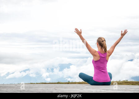 junge Frau am Gipfel des Berges zu meditieren Stockfoto