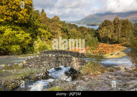 Ashness Brücke im frühen Herbst im englischen Lake District. Derwent Water und die Skiddaw-Range sind im Hintergrund zu sehen. Stockfoto