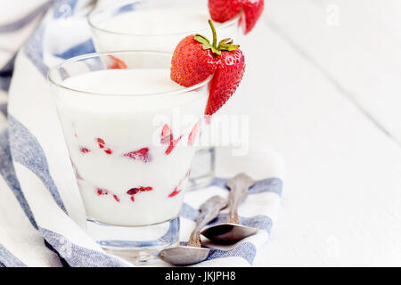 Dessert Joghurt und Erdbeer-Schichten in einem Glas auf eine blau gestreifte Serviette auf einem weißen Hintergrund. Stockfoto