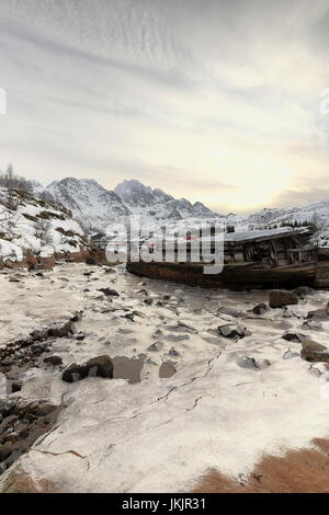 Schiffbrüchige Holzboot gestrandet-Sildpolltjonna Bucht unten-S.shore Sildpollnes Halbinsel-Austnesfjorden. Rulten-Langstrandtindan mts.background. Vagan Stockfoto