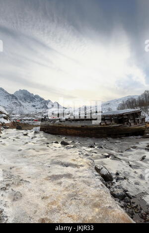 Schiffbrüchige Holzboot gestrandet-Sildpolltjonna Bucht unten-S.shore Sildpollnes Halbinsel-Austnesfjorden. Rulten-Langstrandtindan mts.background. Vagan Stockfoto