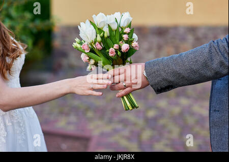 Bräutigam gibt der Braut Hochzeit Blumenstrauß. Stockfoto