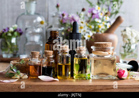 Auswahl von ätherischen Ölen, mit Kräutern und Blumen im Hintergrund Stockfoto