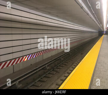 Blick auf die Bahngleise vom Bahnsteig in einer New York City U-Bahnstation. Weiße U-Bahnfliesen und eine gestrichene gelbe Linie auf dem Bahnsteig in NYC. Stockfoto