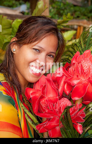 Porträt einer schönen philippinische Frau mit einem wunderschönen Lächeln hält einen Blumenstrauß rote Philippine Wachs, Etlingera Elatior. -Modell veröffentlicht. Stockfoto