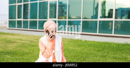 Lächelnde Geschäftsmann reden über ein Handy in Dubai. Arabische Hijab Goovrit Geschäftsmann auf Handy auf der Straße vor dem Hintergrund der Wolkenkratzer von Dubai. Die Frau trägt eine schwarze abaya Stockfoto