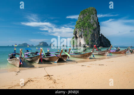 KRABI, THAILAND - 5 Dezember: Bunte Longtailboote an schönen Ao Nang Strand auf einem Hintergrund des blauen Himmels und azurblauen Meer und Kalkstein Felsen, Phi Stockfoto