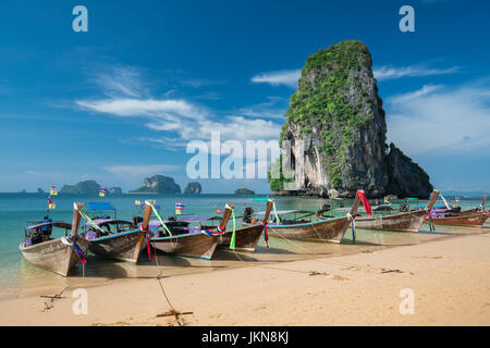 KRABI, THAILAND - 5 Dezember: Bunte Longtailboote an schönen Ao Nang Strand auf einem Hintergrund des blauen Himmels und azurblauen Meer und Kalkstein Felsen, Phi Stockfoto