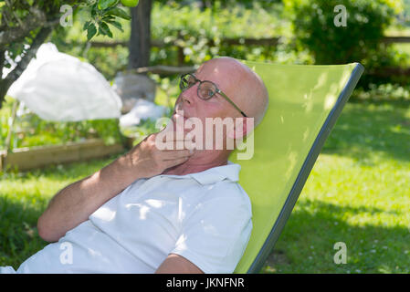 Entspannen im Liegestuhl in seinem Garten, Sommerzeit Senior woman Stockfoto