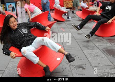 New York, uns. 24. Juli 2017. New York, NY, USA. –-24. Juli 2017 jung und jung gebliebene Besucher zum Times Square hielt einen Augenblick inne, mittags Spaß mit Magis gesponnen Stuhl. Die aufrechte gesponnen Stühle ist ein faszinierender Stuhl, der sieht eher aus wie ein skulpturales Gefäß als ein Sitz. Aber wenn es auf seiner Seite lehnt, bildet es einen komfortable Stuhl, mit dem Sie die rock seitliche oder drehen. Bildnachweis: G. Ronald Lopez /DigiPixsAgain.us/Alamy Live-Nachrichten Stockfoto