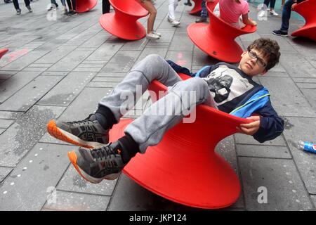 New York, uns. 24. Juli 2017. New York, NY, USA. –-24. Juli 2017 jung und jung gebliebene Besucher zum Times Square hielt einen Augenblick inne, mittags Spaß mit Magis gesponnen Stuhl. Die aufrechte gesponnen Stühle ist ein faszinierender Stuhl, der sieht eher aus wie ein skulpturales Gefäß als ein Sitz. Aber wenn es auf seiner Seite lehnt, bildet es einen komfortable Stuhl, mit dem Sie die rock seitliche oder drehen. Bildnachweis: G. Ronald Lopez /DigiPixsAgain.us/Alamy Live-Nachrichten Stockfoto