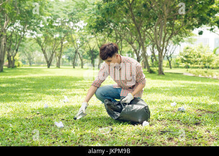 Junge asiatische Mann in gelbe Gummihandschuhe, Hausmüll in die kleinen Müllbeutel Stockfoto