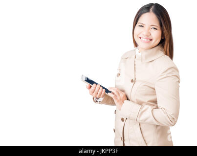 asiatische Frau trägt braune Jacke und hält Tablet isoliert auf weiss Stockfoto