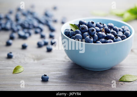 Kleine Schale mit Bio Heidelbeeren auf Holztisch. Frische Heidelbeeren in einer kleinen Schüssel auf einem rustikalen Holztisch. Stockfoto