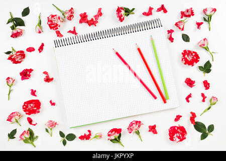 Offenen Spiral-Notizbuch mit Farbstiften und Blumenrahmen auf weißem Hintergrund. Flach legen, Top Aussicht Stockfoto