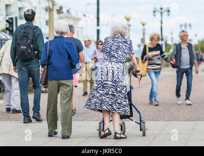 Rollator Gehhilfe. Ältere Frau gehen mit einer fahrbaren Gehhilfe oder fahrbare Gehhilfe in England, Großbritannien. Stockfoto