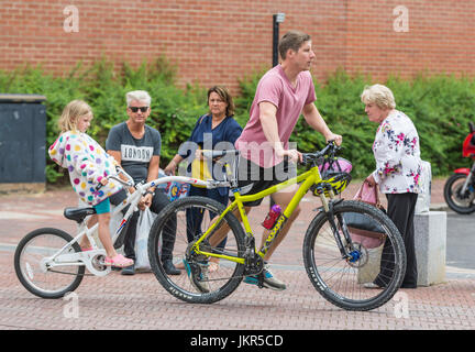 Fahrradanhänger für ein Kind hinter ein Erwachsener Radfahrer fahren mitkommen. Stockfoto