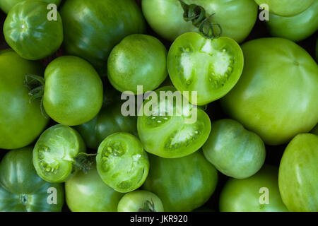 Grüne Tomaten. Hintergrund von grünen Tomaten mit grünen Tomaten schneiden In halbe, Ansicht von oben. Leuchtend grüne Farbe. Stockfoto