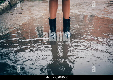 Geringen Teil der Teenager tragen Gummistiefel in Pfütze im Regen stehen Stockfoto