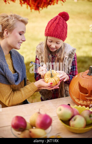 Mutter hilft Tochter in einen Kürbis dekorieren Stockfoto