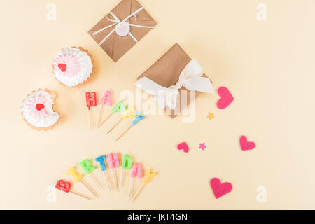 Draufsicht von happy Birthday Schriftzug, Umschläge mit Bändern und Herzen Symbole auf rosa, Geburtstags-Party-Konzept Stockfoto