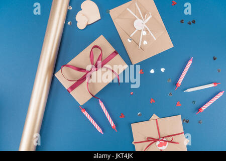 Draufsicht der Geschenk-Box, Umschläge, Kerzen und Geschenkpapier isoliert auf blau, Geburtstag Party Konzept Stockfoto