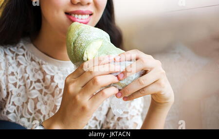 Asiatische Mädchen essen grüner Tee aromatisiert Brot in der Bäckerei Stockfoto