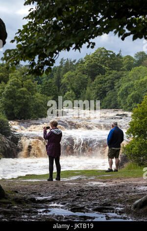 Zwei Menschen, die genießen des Spektakels des Flusses Tees in Flut bei geringer Kraft, Bowlees, Teesdale, County Durham UK Stockfoto