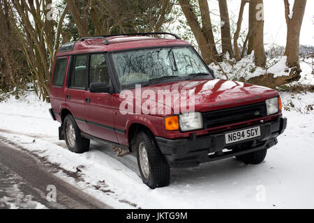 Land Rover Discovery im Schnee am Straßenrand Stockfoto