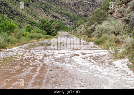 Die Straße von Pilar in der Nähe von Taos in New Mexico entlang des Flusses durch die Schlucht des Rio Grande ist nach starken Regenfällen überflutet. Stockfoto