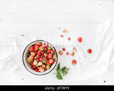 Wilde Erdbeeren in rustikalen Metallschale auf weißem Holz Hintergrund Stockfoto