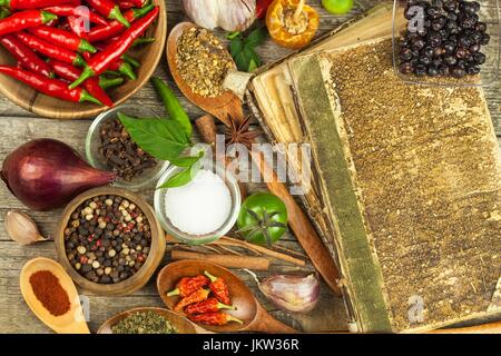 Altes Buch Rezepte kochen. Kulinarischen Hintergrund und Rezept Buch mit verschiedenen Gewürzen auf Holztisch Stockfoto