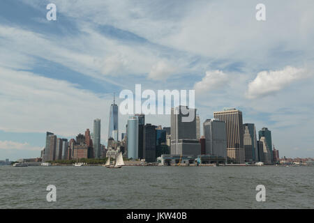 Ein Foto von der Skyline von Manhattan, wie von Governors Island, New York City zu sehen. Im Vordergrund ist ein altes Segelschiff zu sehen. Stockfoto