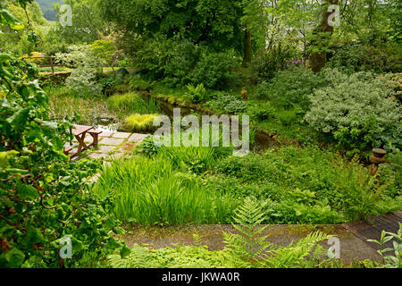 Spektakuläre Gemeinschafts-Garten mit Wasserspiel, Pflasterarbeiten, Picknick-Tisch und Bäume spiegeln sich im Wasser des ruhigen Pool - in Schottland Stockfoto