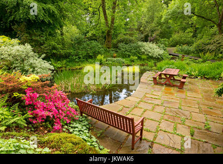 Spektakuläre Gemeinschafts-Garten mit Wasserspiel, Pflasterarbeiten, Picknick-Tisch und Bäume spiegeln sich im Wasser des ruhigen Pool - in Schottland Stockfoto