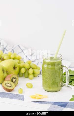Grünen Smoothie in Glas, Äpfel, Sellerie, Trauben, Spinat und Kiwi auf weißes Tuch Hintergrund gemacht. Gesundes Getränk Konzept Stockfoto