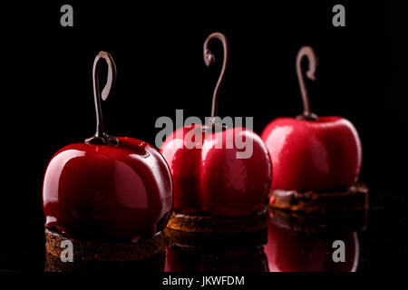 Glossy mousse Kuchen in Form von Kirschen auf schwarzem Hintergrund Stockfoto