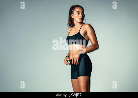 Porträt von Fitness-Frau von Sportswear über grauen Hintergrund stehen und wegsehen. Hispanische weibliches Model im Studio. Stockfoto