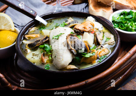 Meeresfrüchte-Fisch-Suppe in Tonschalen serviert mit Zitrone und Koriander. Nahaufnahme, Textfreiraum. Stockfoto